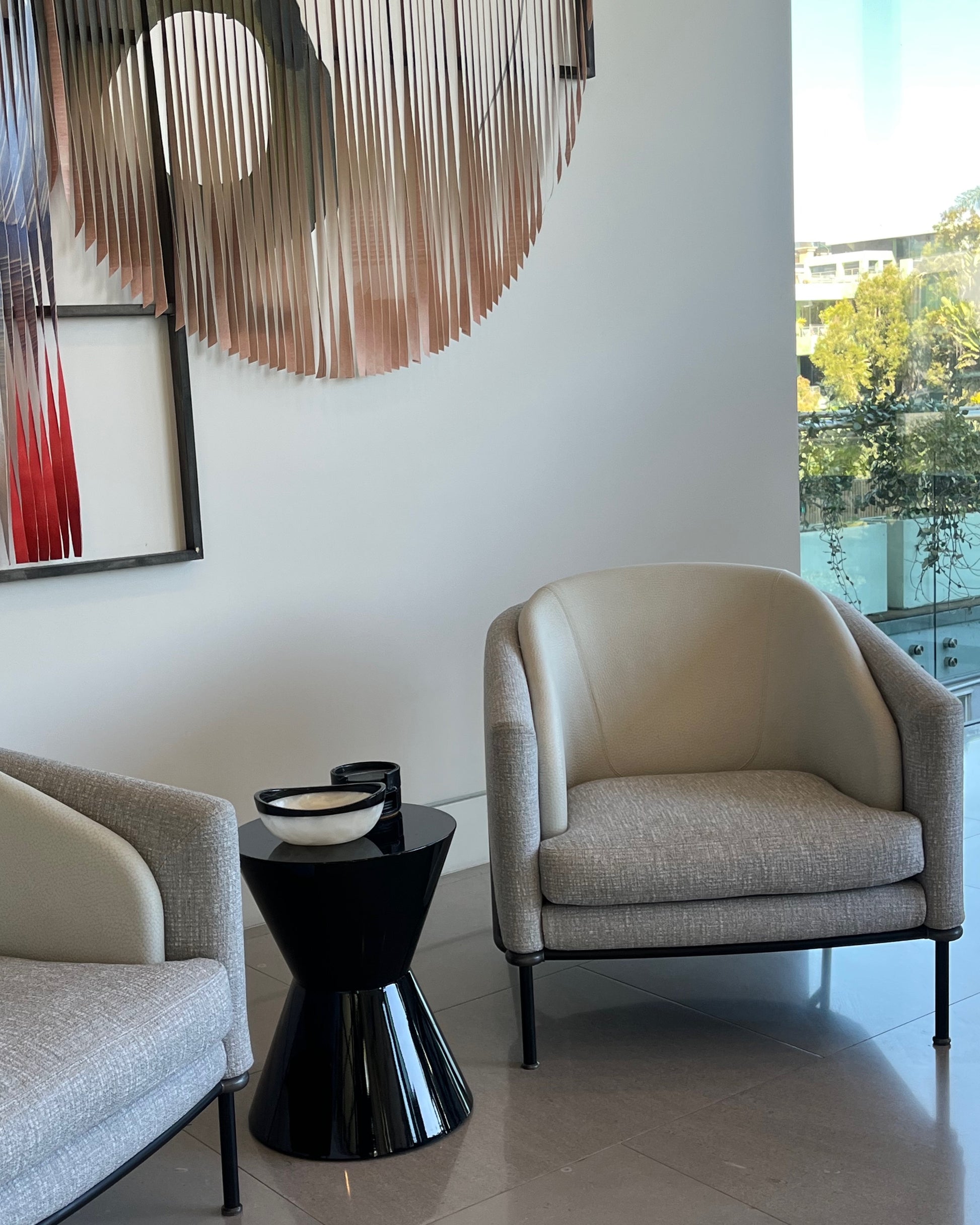 Modern living room with beige armchair, black side table, and abstract wall art.