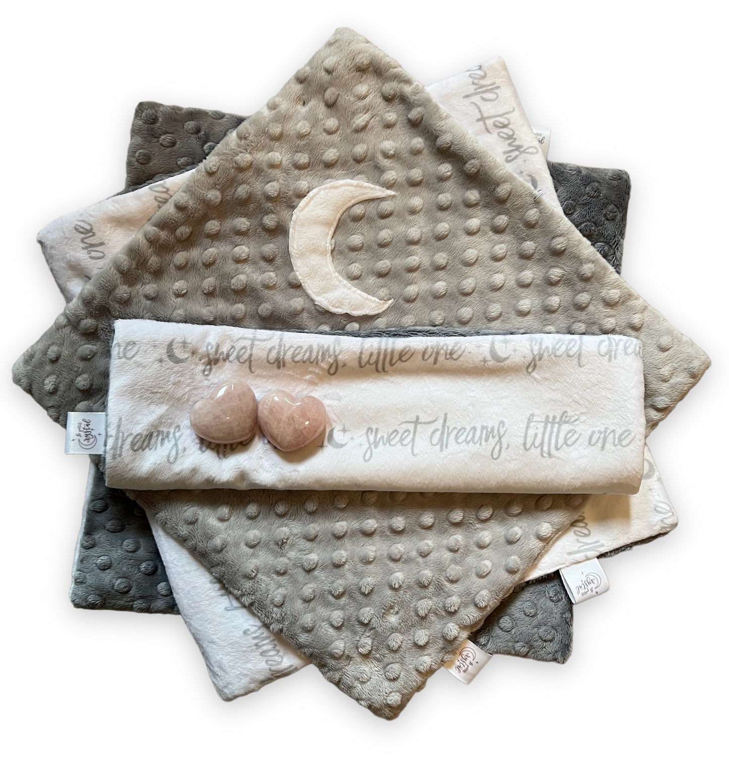 Stack of soft textured baby blankets with moon and heart designs on a white background
