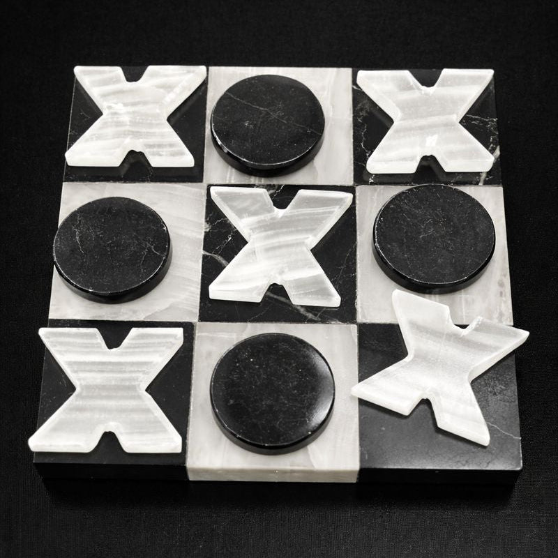 Black and white onyx tic tac toe board with carved stone X and O pieces on black background