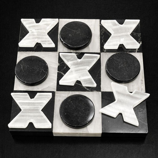 Black and white onyx tic tac toe board with carved stone X and O pieces on black background