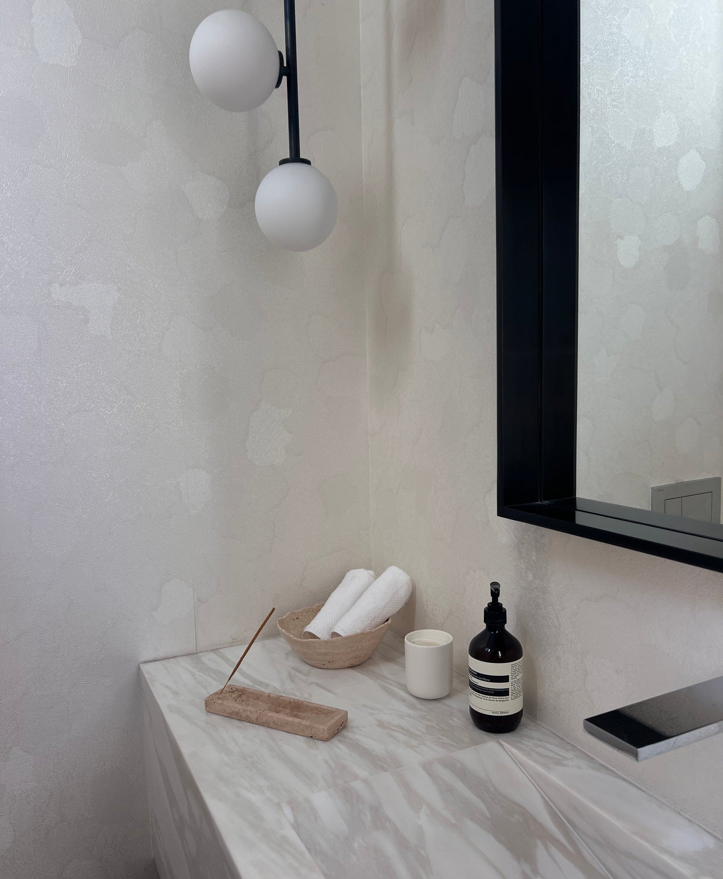 Bathroom counter with toiletries and decor items against a light gray wall.