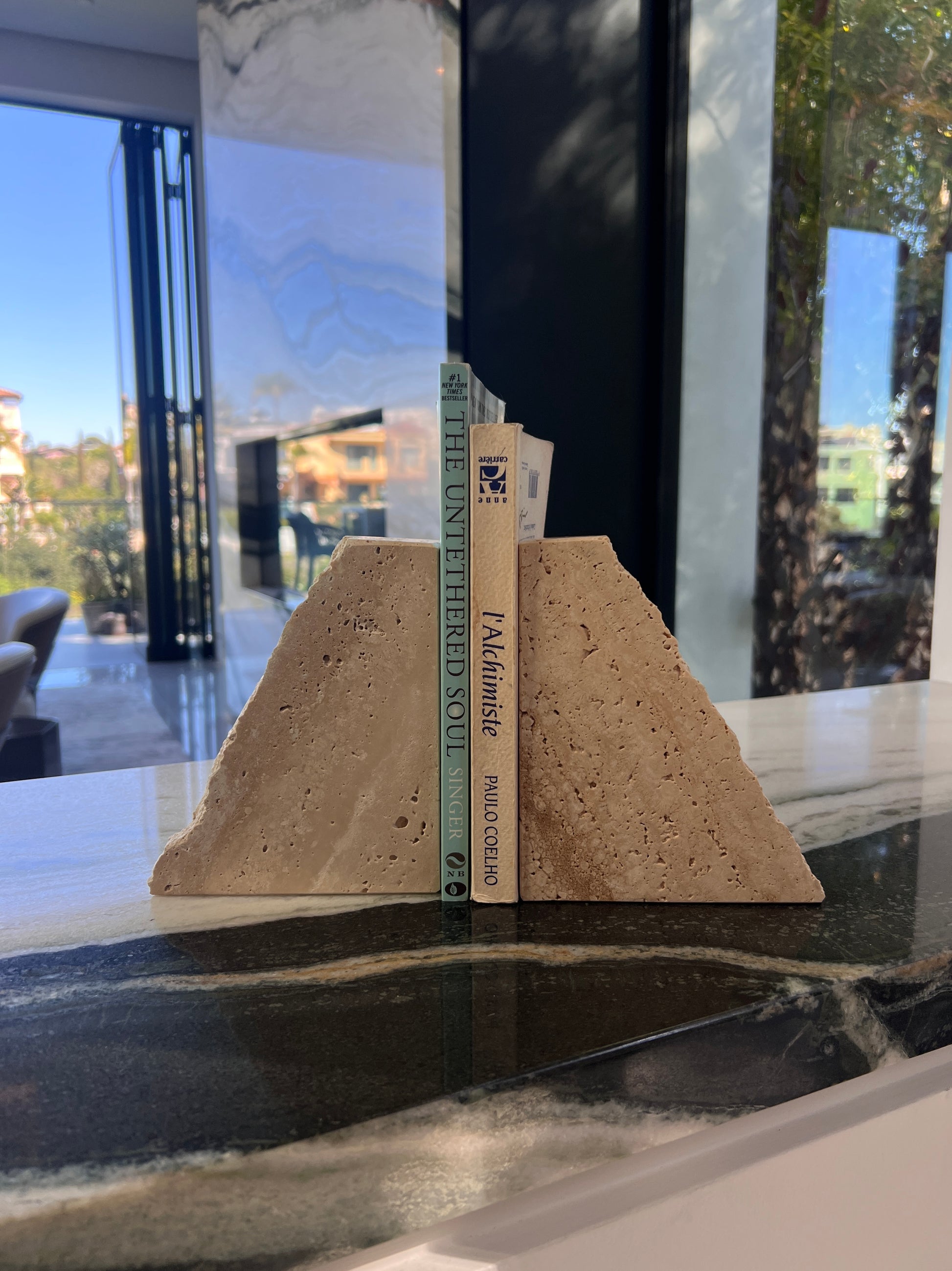 Bookend shaped like a sand dune on a marble surface with a blurred outdoor background