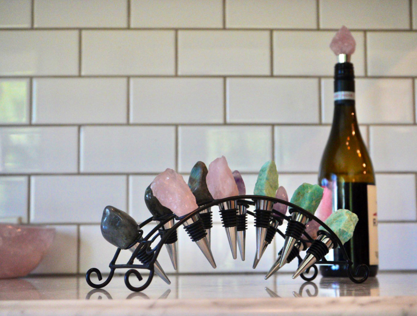 Decorative crystal bottle stoppers in iron holder on a kitchen counter.