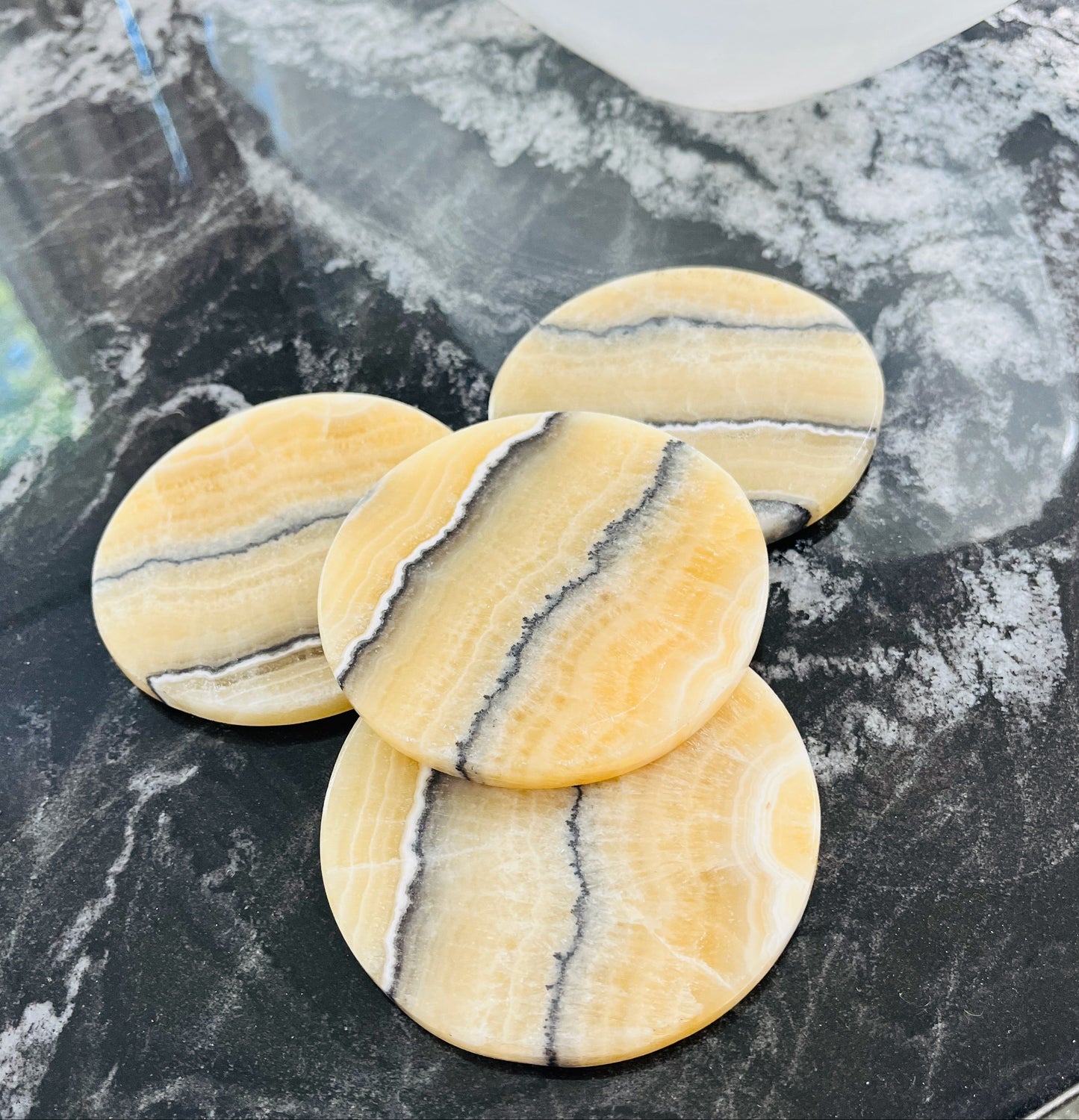 Yellow Calcite Coaster with marble pattern on a black marble surface