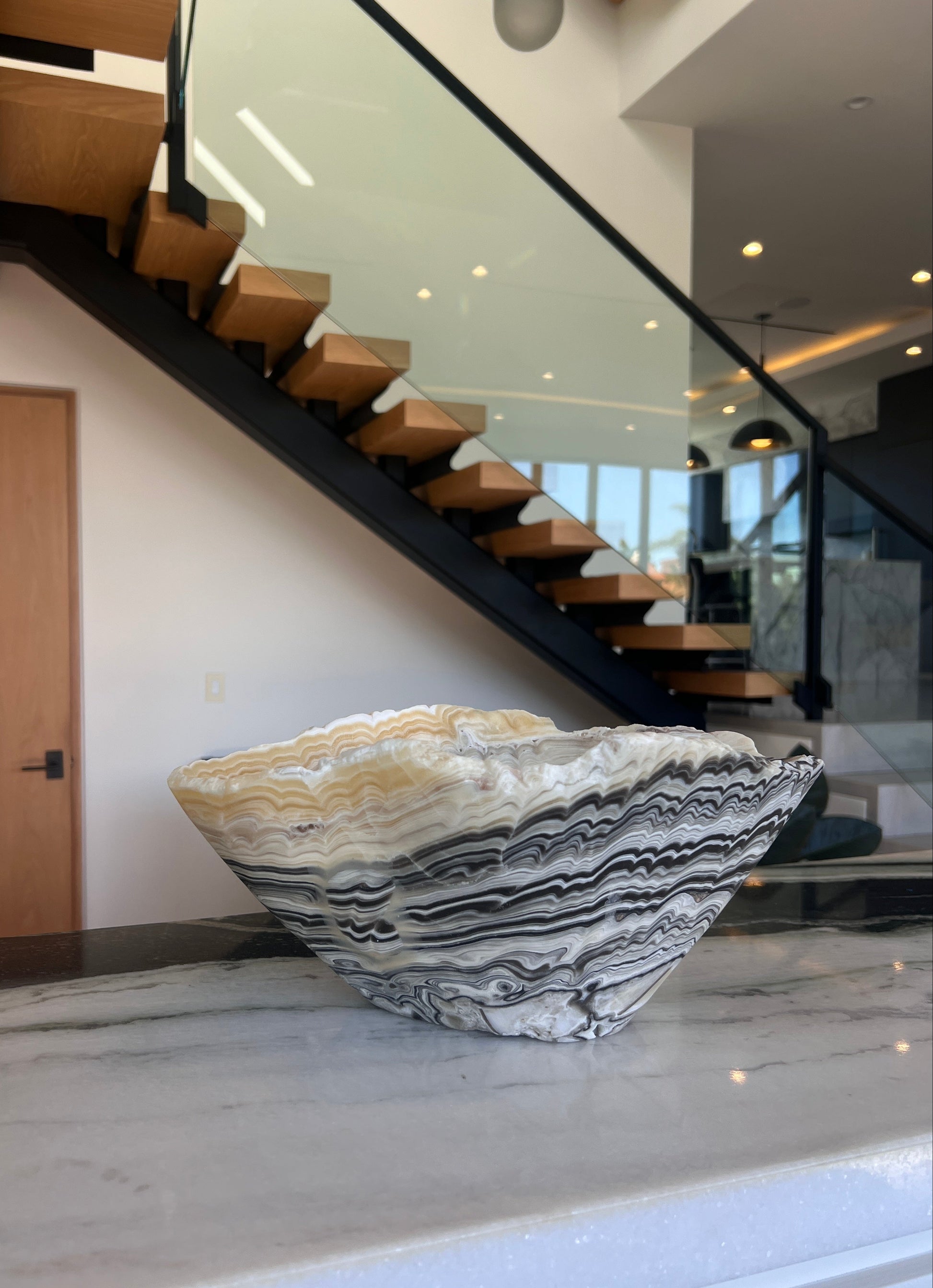 Decorative stone bowl on a marble surface with a staircase in the background