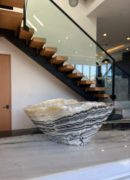 Decorative stone bowl on a marble surface with a staircase in the background